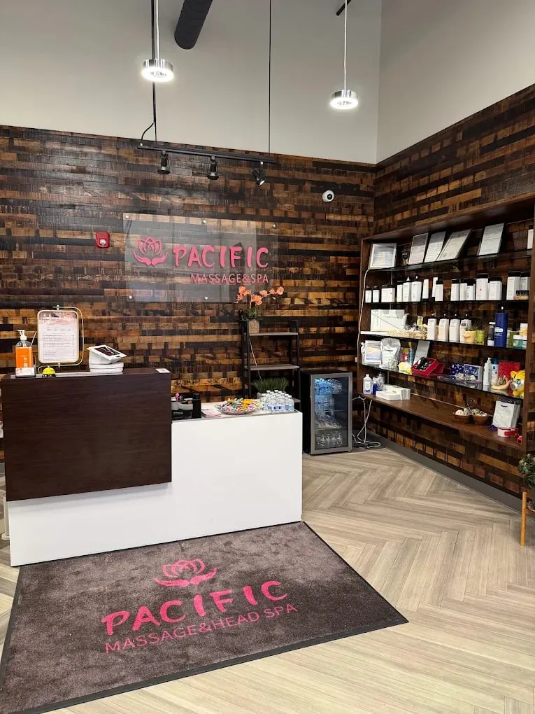 Reception at Pacific Massage & Head Spa in Redmond — reclaimed wood wall, pink lotus sign and retail shelves of scalp and skin care