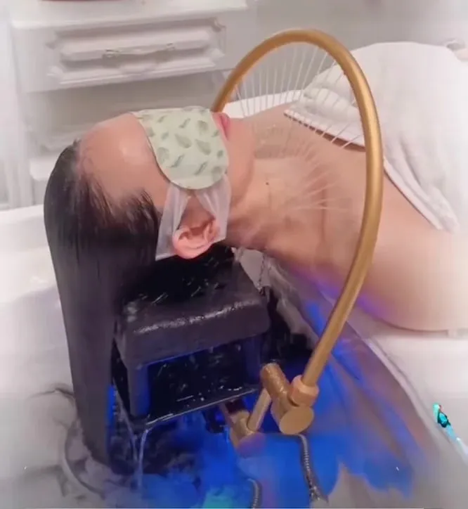Warm water running through a guest's hair at the gold rinse fixture during a head spa session in Redmond, WA
